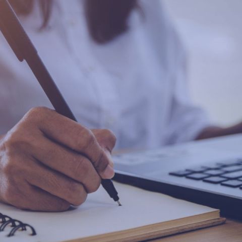 A person writing in a notes during studying The Knwoledge Hub free courses